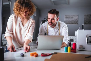Moda tasarım stüdyosunda dizüstü bilgisayar kullanarak proje çalışmaları sırasında profesyonel terziler