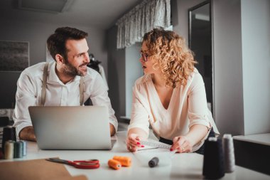 Moda tasarım stüdyosunda dizüstü bilgisayar kullanarak proje çalışmaları sırasında profesyonel terziler