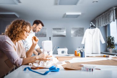 Moda tasarım stüdyosunda proje çalışmaları sırasında profesyonel terziler, dikiş ekipmanları kullanarak