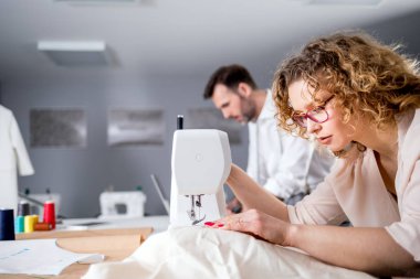 Moda tasarım stüdyosunda proje çalışmaları sırasında profesyonel terziler, dikiş ekipmanları kullanarak