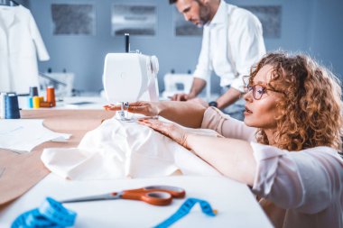 Moda tasarım stüdyosunda proje çalışmaları sırasında profesyonel terziler, dikiş ekipmanları kullanarak
