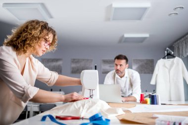 Moda tasarım stüdyosunda proje çalışmaları sırasında profesyonel terziler, dikiş ekipmanları kullanarak