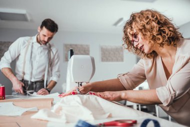 Moda tasarım stüdyosunda proje çalışmaları sırasında profesyonel terziler, dikiş ekipmanları kullanarak