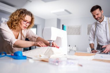 Moda tasarım stüdyosunda proje çalışmaları sırasında profesyonel terziler, dikiş ekipmanları kullanarak