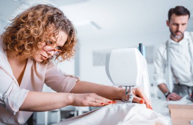 Moda tasarım stüdyosunda proje çalışmaları sırasında profesyonel terziler, dikiş ekipmanları kullanarak