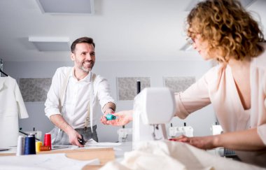 Moda tasarım stüdyosunda proje çalışmaları sırasında profesyonel terziler, dikiş ekipmanları kullanarak