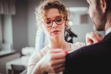 Moda tasarım stüdyosunda dikiş takım elbise için müşteri ölçmek için bant kullanarak profesyonel terzi