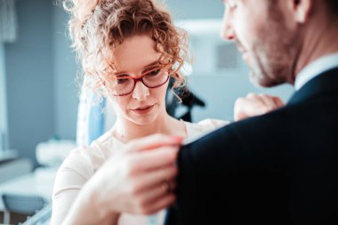 Moda tasarım stüdyosunda dikiş takım elbise için müşteri ölçmek için bant kullanarak profesyonel terzi