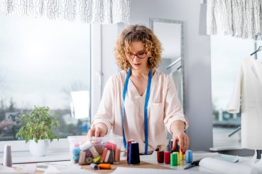 Moda tasarım atölyesinde çalışma masası üzerinde profesyonel kadın terzi