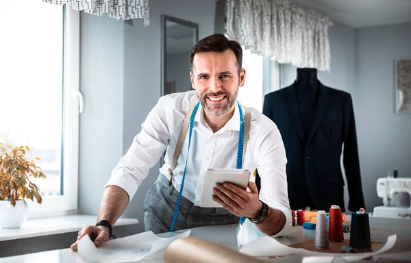 Çalışma sırasında dijital tablet kullanarak çalışma masası üzerinde terzi, atölyede modern moda tasarımcısı