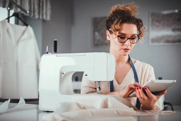 Tailor during work using digital tablet, modern fashion designer at workshop