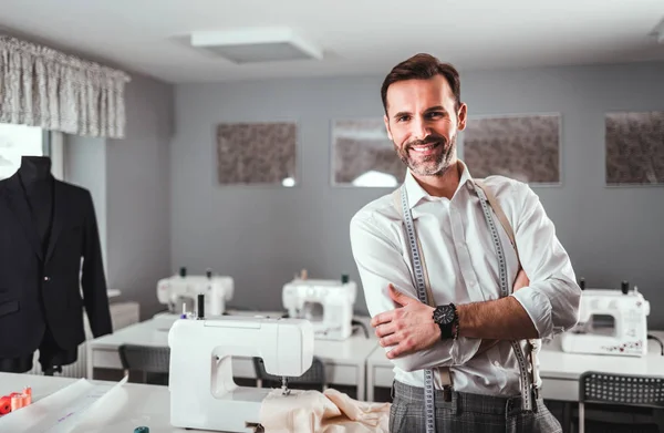 Gülümseyen terzi dükkanı sahibi atölye masası, moda tasarım iş üzerinde duran