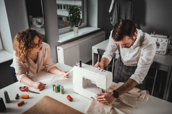 Moda tasarım stüdyosunda dikiş makinesi kullanarak proje çalışmaları sırasında profesyonel terziler