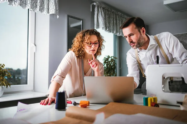 Moda tasarım stüdyosunda dizüstü bilgisayar kullanarak proje çalışmaları sırasında profesyonel terziler