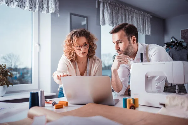 Moda tasarım stüdyosunda dizüstü bilgisayar kullanarak proje çalışmaları sırasında profesyonel terziler