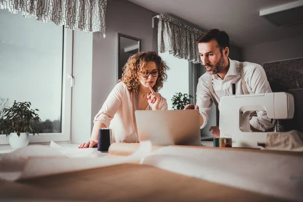 Moda tasarım stüdyosunda dizüstü bilgisayar kullanarak proje çalışmaları sırasında profesyonel terziler