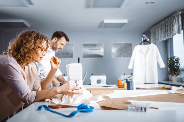 Moda tasarım stüdyosunda proje çalışmaları sırasında profesyonel terziler, dikiş ekipmanları kullanarak