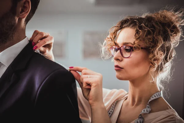 Atölyede dikiş elbisesi için müşteri ölçmek için bant kullanan profesyonel terzi