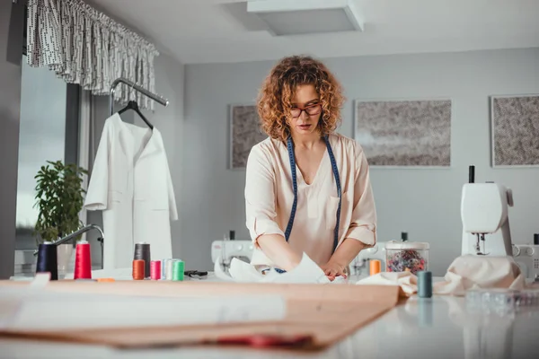 Moda tasarım atölyesinde çalışma masası üzerinde profesyonel kadın terzi
