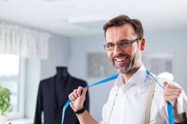 Kamera bakarak ölçüm bandı ile Mutlu terzi dükkanı sahibi