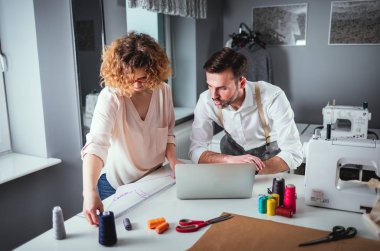 Moda tasarım stüdyosunda dizüstü bilgisayar kullanarak proje çalışmaları sırasında profesyonel terziler