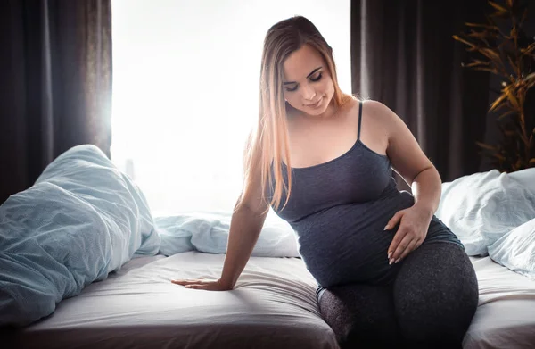 Mujer Embarazada Joven Sentada Cama Tocando Vientre Concepto Expectativa Infantil —  Fotos de Stock