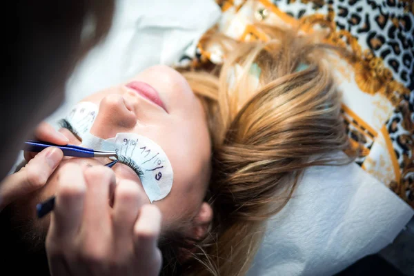 Güzellik salonunda uzatma kirpik leri uygulayan erkek güzellik uzmanı