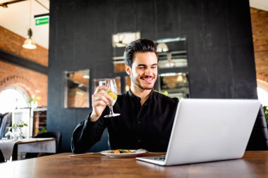 Başarılı yakışıklı işadamı yeme ve restoranda dizüstü bilgisayar kullanma