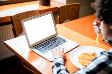 Restoranda masada dizüstü boş boş ekran, yemek yaparken bilgisayar kullanarak genç adam