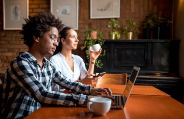 Cafe 'de çok ırklı iş ekibi toplantısı, dizüstü bilgisayar ve akıllı telefon kullanarak çalışma
