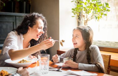 Latin anne ve kızı restoranda birlikte öğle yemeği yeme, çok ırklı aile eğlenmek