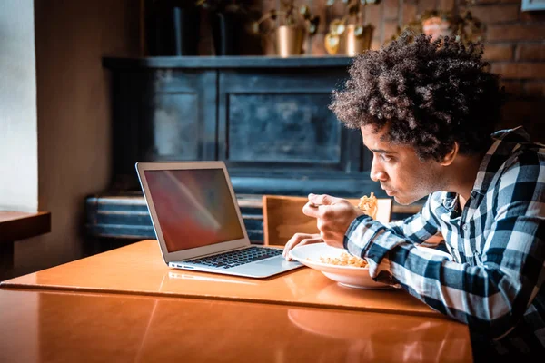 Pantalla vacía de la computadora portátil en la mesa en el restaurante, hombre joven usando la computadora mientras come — Foto de Stock