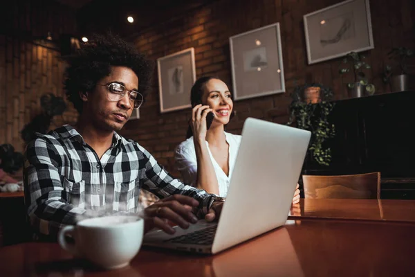 Reunión del equipo de negocios multiétnicos en la cafetería, trabajando con computadora portátil y teléfono inteligente — Foto de Stock