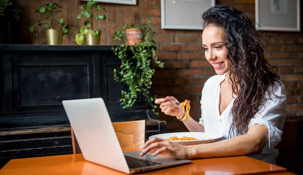 Mujer joven latina que trabaja en el ordenador portátil en el restaurante, comer descanso durante el trabajo — Foto de Stock