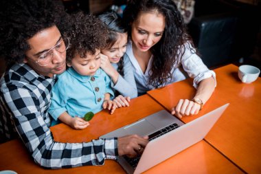 Happy multiethnic family having fun while using laptop together