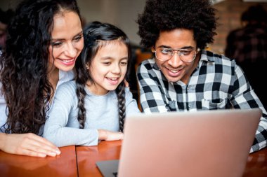 Happy multiethnic family having fun while using laptop together