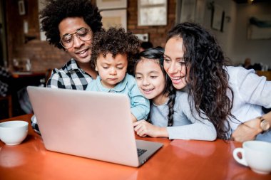 Happy multiethnic family having fun while using laptop together