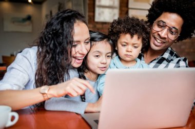 Happy multiethnic family having fun while using laptop together