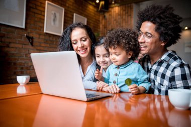 Happy multiethnic family having fun while using laptop together