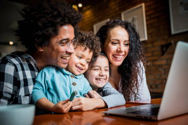 Happy multiethnic family having fun while using laptop together