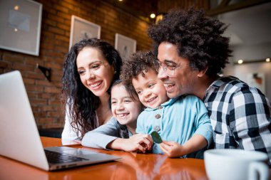 Happy multiethnic family having fun while using laptop together