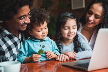 Happy multiethnic family having fun while using laptop together
