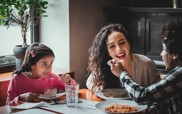 Happy african american family eating lunch together at restaurant and having fun