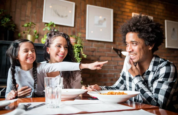 Happy african american family eating lunch together at restaurant and having fun