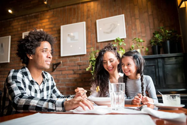 Happy african american family eating lunch together at restaurant and having fun