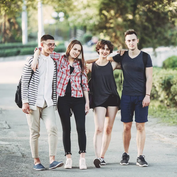 Amigos con mochilas abrazándose caminando por la ciudad — Foto de Stock