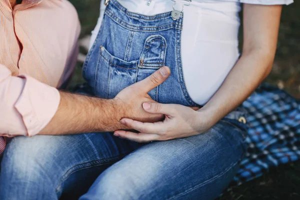 Manos masculinas y femeninas abrazando el vientre de la mujer embarazada — Foto de Stock