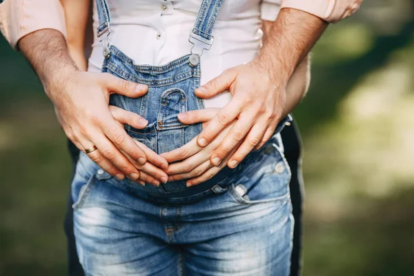 Male and female hands hugging pregnant woman belly