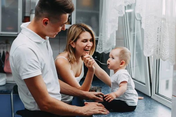 Genitori che nutrono la loro adorabile figlia con cucchiaio — Foto Stock