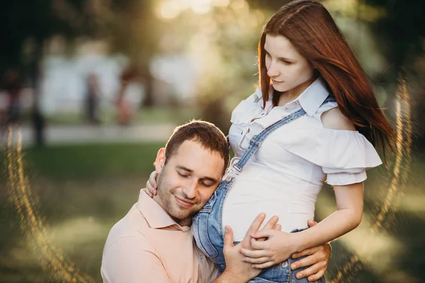 Pai ouvindo bebê se movendo dentro da barriga grávida — Fotografia de Stock